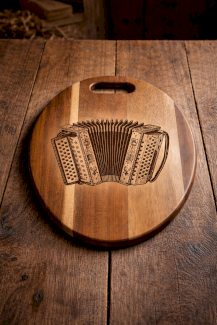 Rundes Schneidebrett aus Nussbaum und Ahorn mit Handorgel-Gravur – Ø 17–20 cm / Länge 30 cm - Gratisinserat.ch